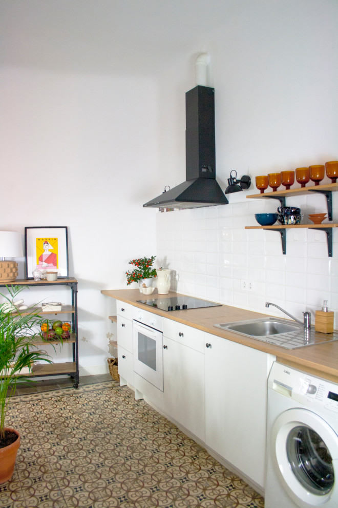 Photo of a small contemporary single-wall kitchen in Madrid with a drop-in sink, flat-panel cabinets, white cabinets, wood benchtops, white splashback, porcelain splashback, white appliances, no island, brown floor and beige benchtop.