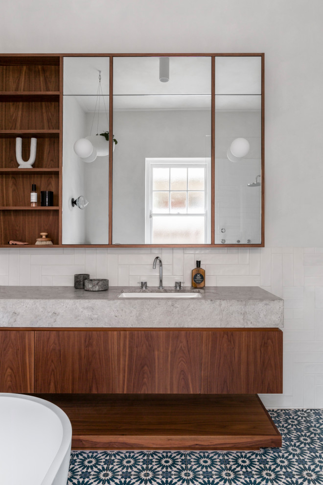 Photo of a contemporary bathroom in Other with flat-panel cabinets, medium wood cabinets, a freestanding tub, white tile, white walls, an undermount sink, blue floor, grey benchtops, a single vanity and a floating vanity.