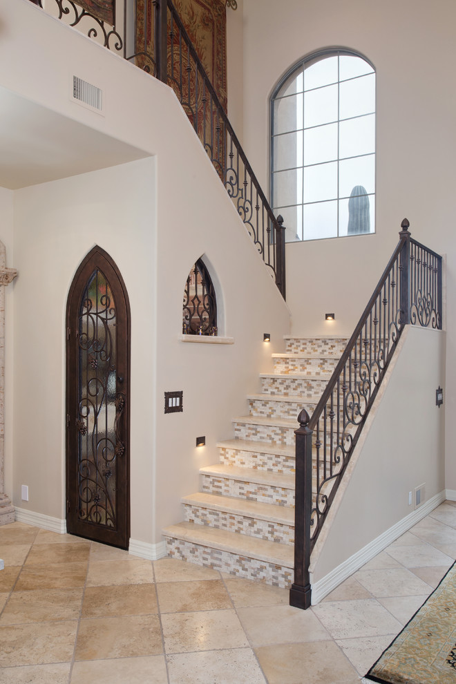 Design ideas for a mid-sized mediterranean travertine u-shaped staircase in Phoenix with tile risers and metal railing.