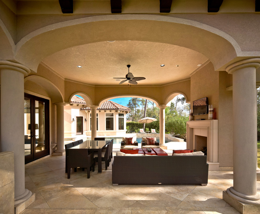 This is an example of an expansive mediterranean backyard patio in Houston with a fire feature, tile and a roof extension.
