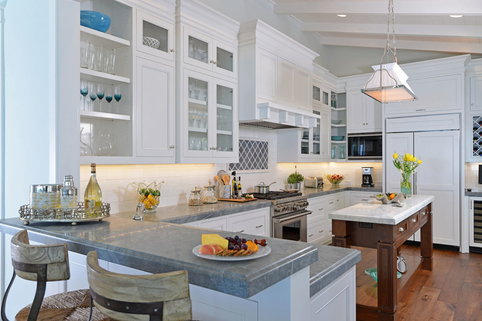 Photo of a beach style l-shaped kitchen in San Diego with open cabinets, white cabinets, white splashback, subway tile splashback, stainless steel appliances, medium hardwood floors and with island.
