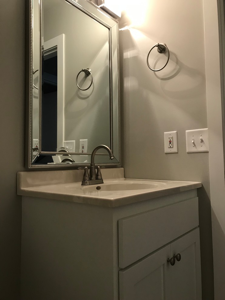 Example of a small trendy vinyl floor and gray floor bathroom design in Minneapolis with shaker cabinets, white cabinets, gray walls, an integrated sink and solid surface countertops