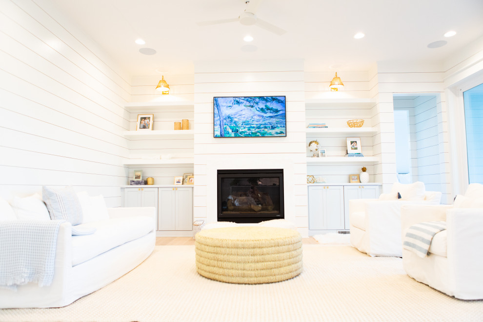 Стильный дизайн: большая открытая гостиная комната в морском стиле с белыми стенами, стандартным камином, фасадом камина из вагонки, телевизором на стене и стенами из вагонки - последний тренд