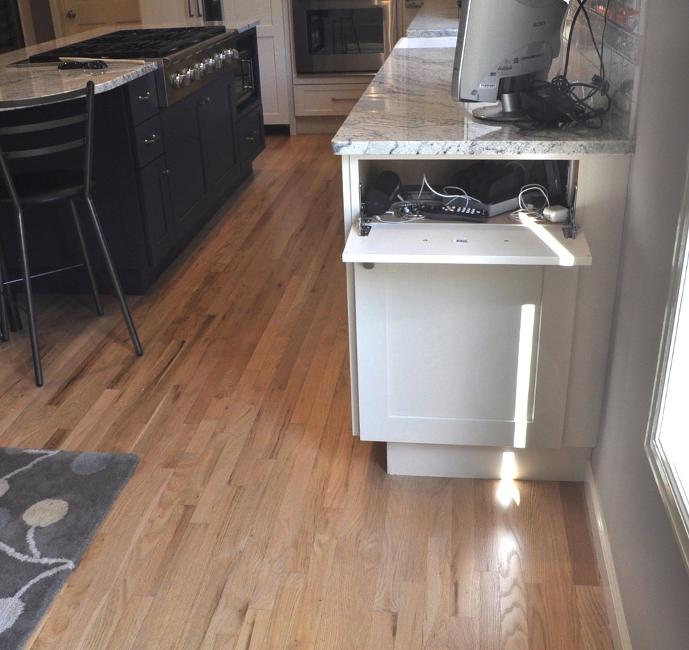 Mid-sized transitional l-shaped light wood floor and brown floor enclosed kitchen photo in Denver with a farmhouse sink, shaker cabinets, white backsplash, ceramic backsplash, an island, white cabinets, marble countertops and stainless steel appliances