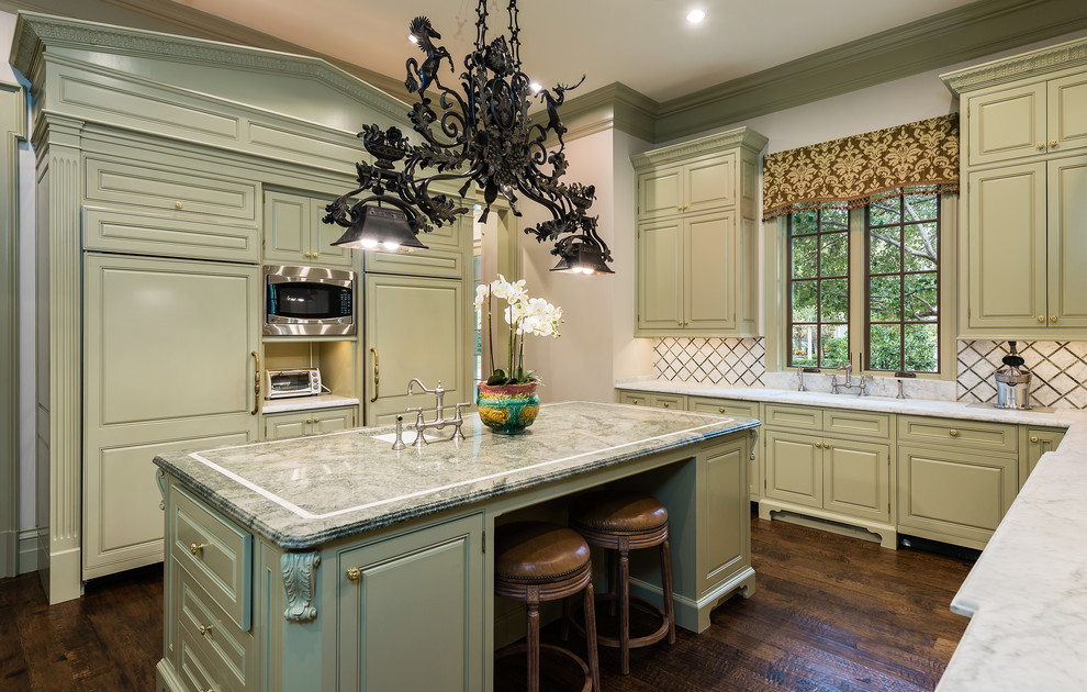 This is an example of a traditional u-shaped kitchen in Dallas with an undermount sink, raised-panel cabinets, green cabinets, dark hardwood floors, with island, brown floor and grey benchtop.