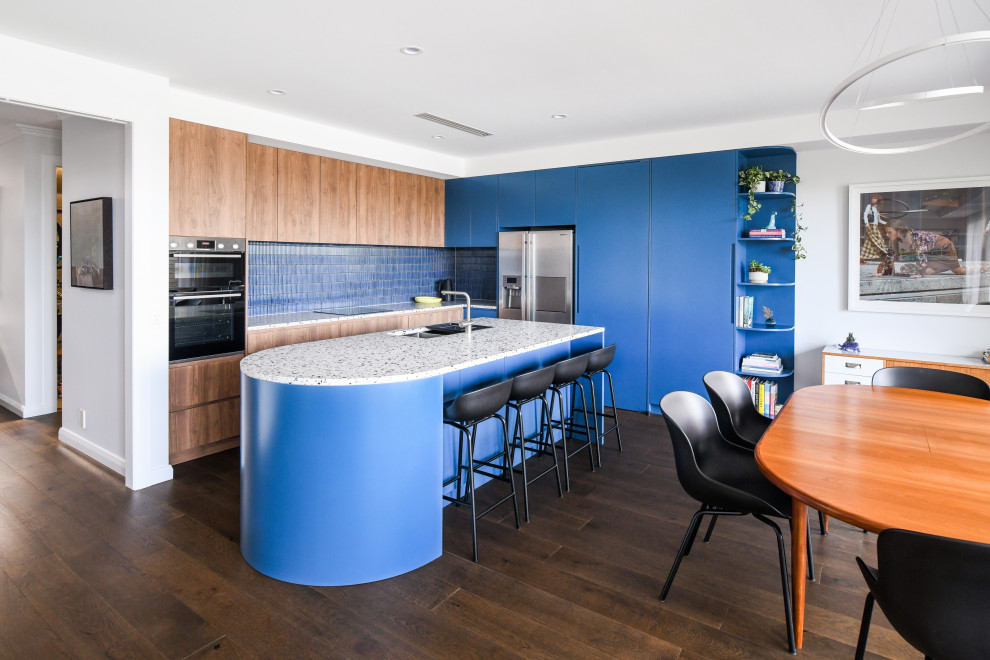 シドニーにある高級な広いエクレクティックスタイルのおしゃれなキッチン (アンダーカウンターシンク、青いキャビネット、テラゾーカウンター、青いキッチンパネル、モザイクタイルのキッチンパネル、シルバーの調理設備、茶色い床、マルチカラーのキッチンカウンター) の写真