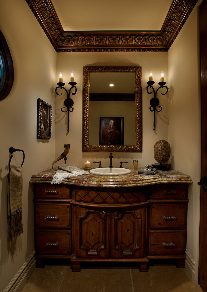 This is an example of a mid-sized mediterranean powder room in Phoenix with furniture-like cabinets, dark wood cabinets, beige tile, stone tile, beige walls, limestone floors, a drop-in sink and granite benchtops.