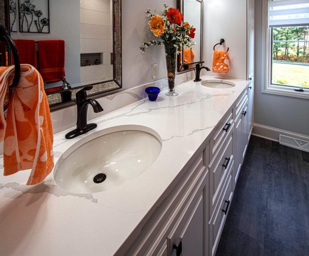 This is an example of a mid-sized transitional 3/4 bathroom in Cleveland with raised-panel cabinets, white cabinets, an alcove tub, a shower/bathtub combo, a two-piece toilet, white tile, porcelain tile, grey walls, wood-look tile, an undermount sink, engineered quartz benchtops, grey floor, a shower curtain, white benchtops, a niche, a double vanity and a built-in vanity.