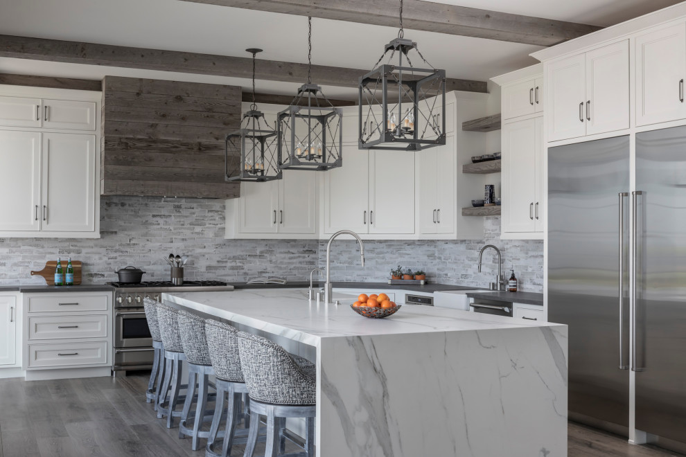 Transitional l-shaped kitchen in Los Angeles with a farmhouse sink, recessed-panel cabinets, white cabinets, grey splashback, stainless steel appliances, dark hardwood floors, with island, grey floor and grey benchtop.