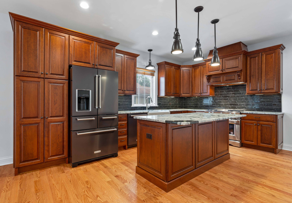 Idéer för att renovera ett mellanstort amerikanskt grå grått kök, med en undermonterad diskho, luckor med upphöjd panel, skåp i mörkt trä, bänkskiva i kvartsit, svart stänkskydd, stänkskydd i keramik, rostfria vitvaror, ljust trägolv, en köksö och brunt golv