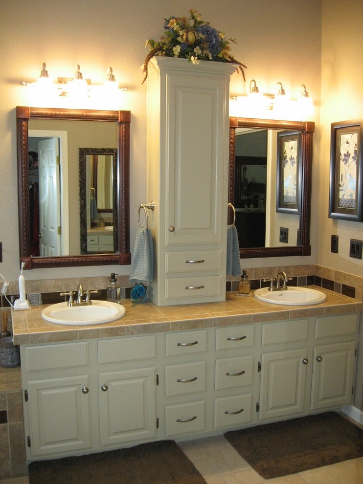 Photo of a large traditional master bathroom in Denver with raised-panel cabinets, white cabinets, beige walls, travertine floors, a drop-in sink, tile benchtops, a drop-in tub, an alcove shower, beige tile, brown tile and ceramic tile.