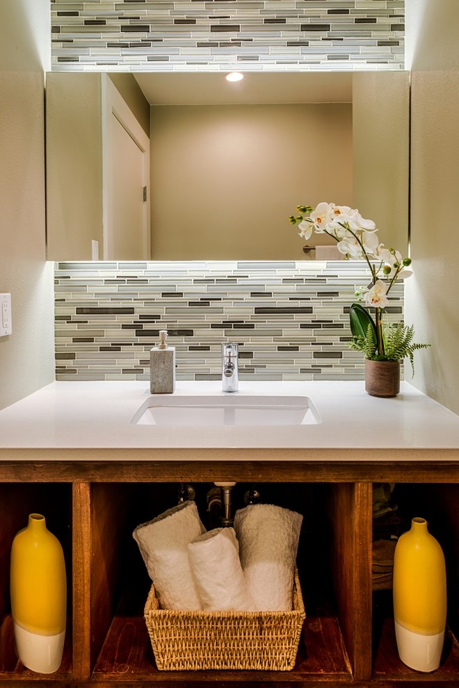 Photo of a small modern bathroom in Austin with an undermount sink, open cabinets, medium wood cabinets, engineered quartz benchtops, a drop-in tub, a one-piece toilet, gray tile, glass tile, white walls and porcelain floors.