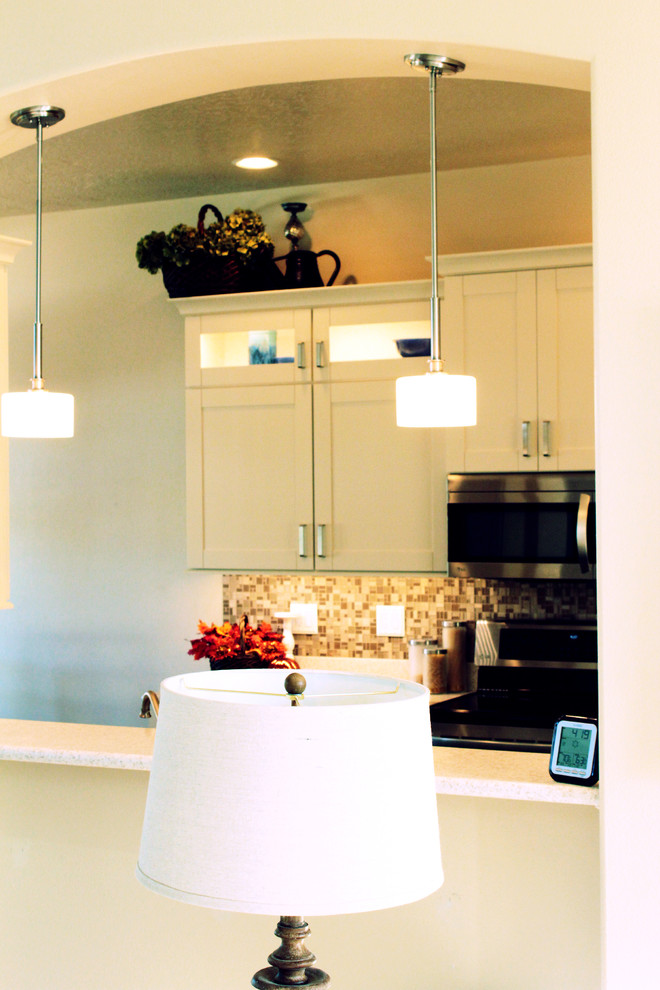 Example of a transitional galley eat-in kitchen design in Boise with an integrated sink, shaker cabinets, white cabinets, solid surface countertops, beige backsplash, glass tile backsplash and stainless steel appliances