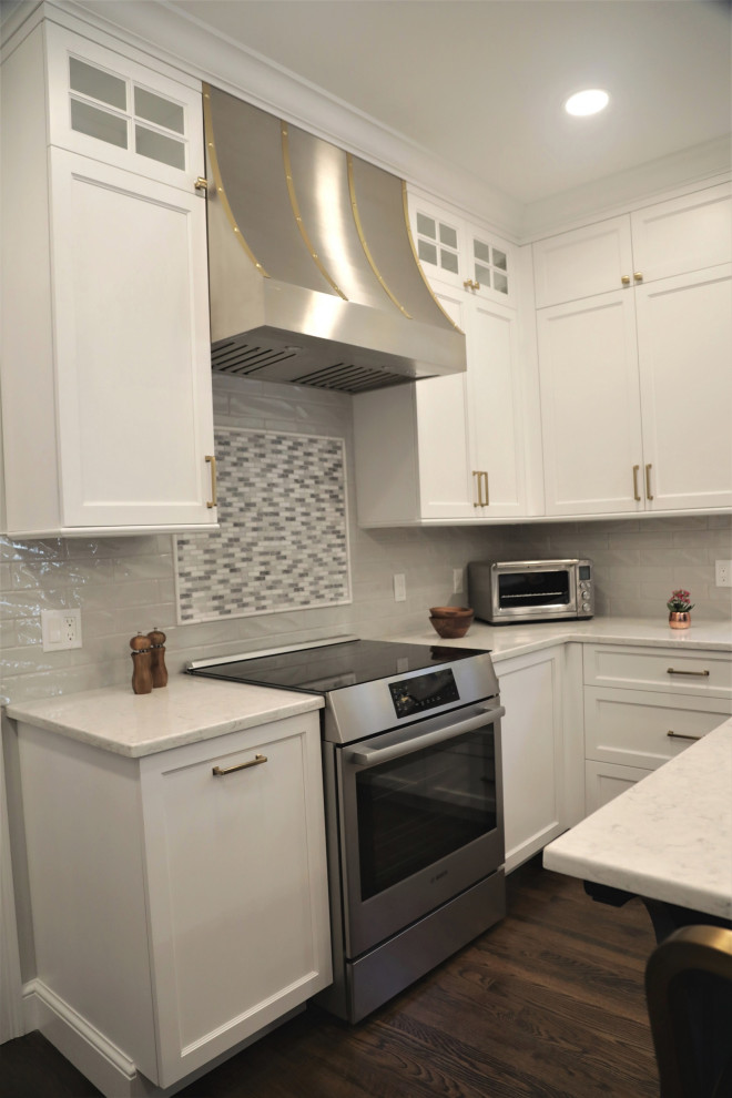 Large beach style u-shaped open plan kitchen in Boston with an undermount sink, recessed-panel cabinets, white cabinets, white splashback, subway tile splashback, stainless steel appliances, dark hardwood floors, with island, brown floor and white benchtop.