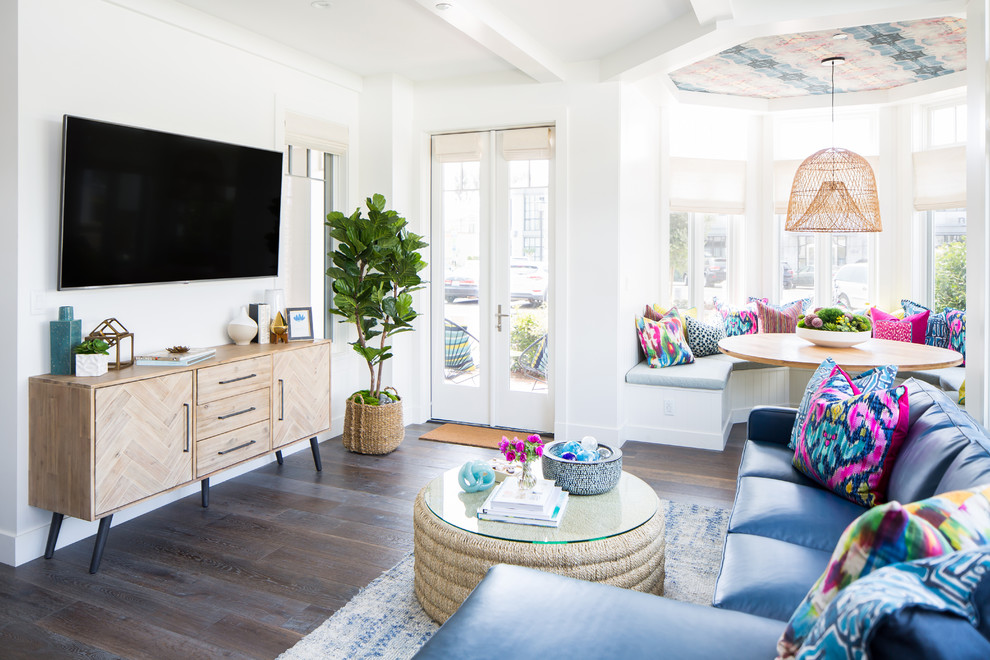 Mid-sized beach style enclosed living room in Orange County with white walls, medium hardwood floors, a wall-mounted tv and brown floor.