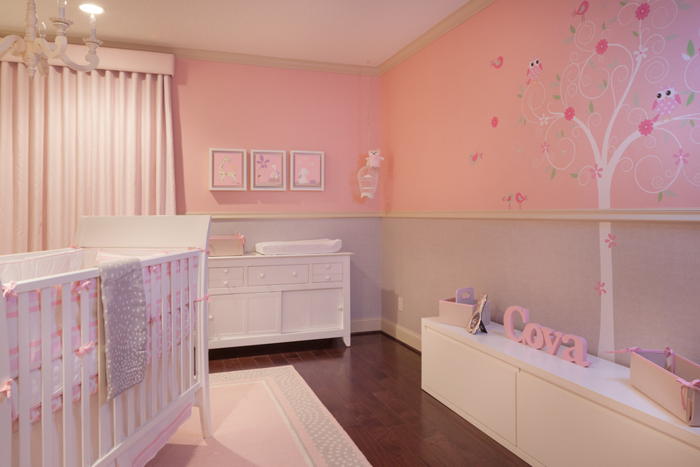 This is an example of a mid-sized modern nursery for girls in Houston with pink walls and medium hardwood floors.