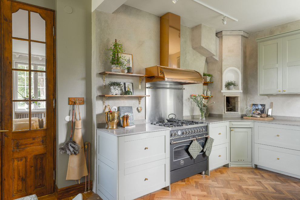 This is an example of a country kitchen in Stockholm with recessed-panel cabinets, green cabinets, granite benchtops, metallic splashback, medium hardwood floors and no island.