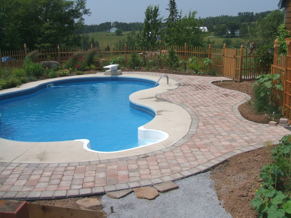 Design ideas for a mid-sized traditional backyard kidney-shaped pool in Montreal with natural stone pavers.