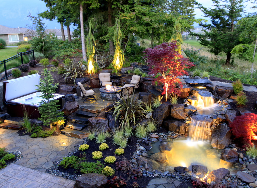 Large traditional backyard garden in Seattle with with waterfall and natural stone pavers.
