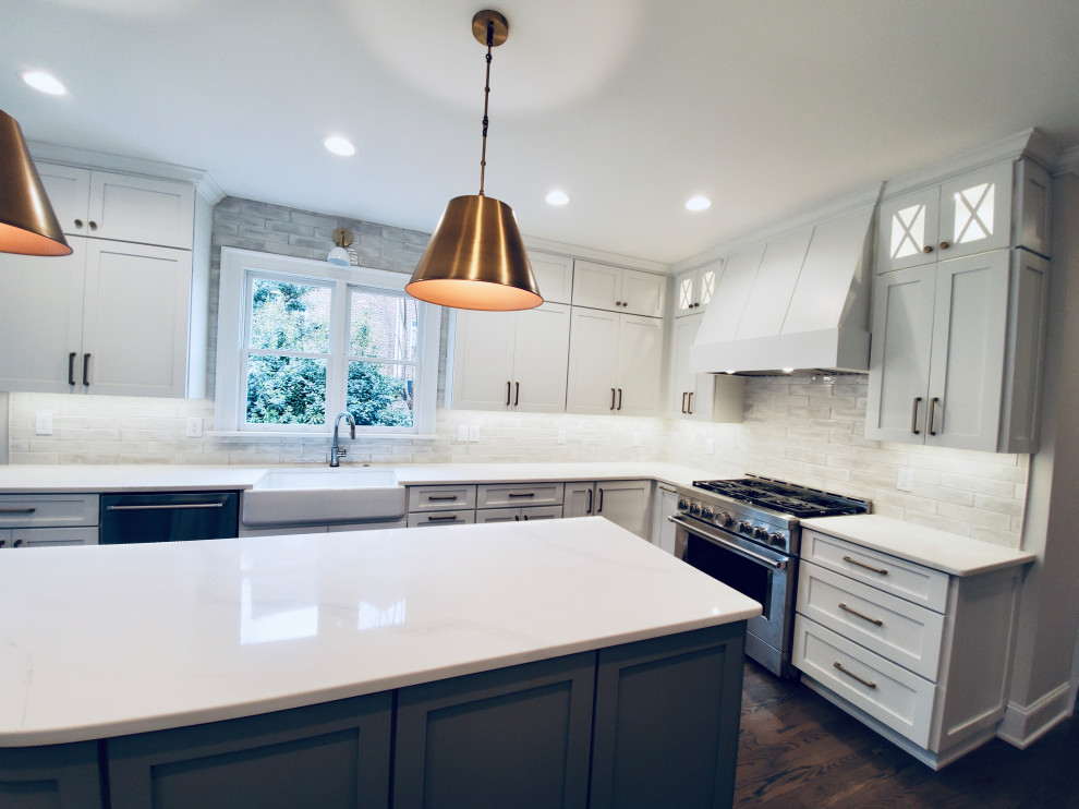 Photo of a large eclectic u-shaped kitchen/diner in Raleigh with a belfast sink, shaker cabinets, white cabinets, composite countertops, white splashback, ceramic splashback, stainless steel appliances, medium hardwood flooring, an island, white worktops and all types of ceiling.