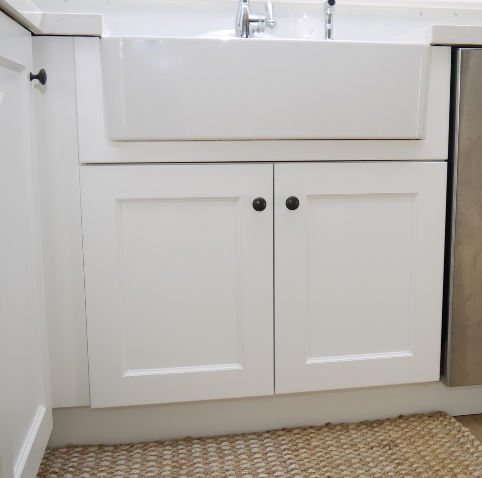 Inspiration for a small transitional l-shaped light wood floor eat-in kitchen remodel in Toronto with a farmhouse sink, shaker cabinets, white cabinets, quartz countertops, white backsplash, ceramic backsplash, stainless steel appliances and a peninsula