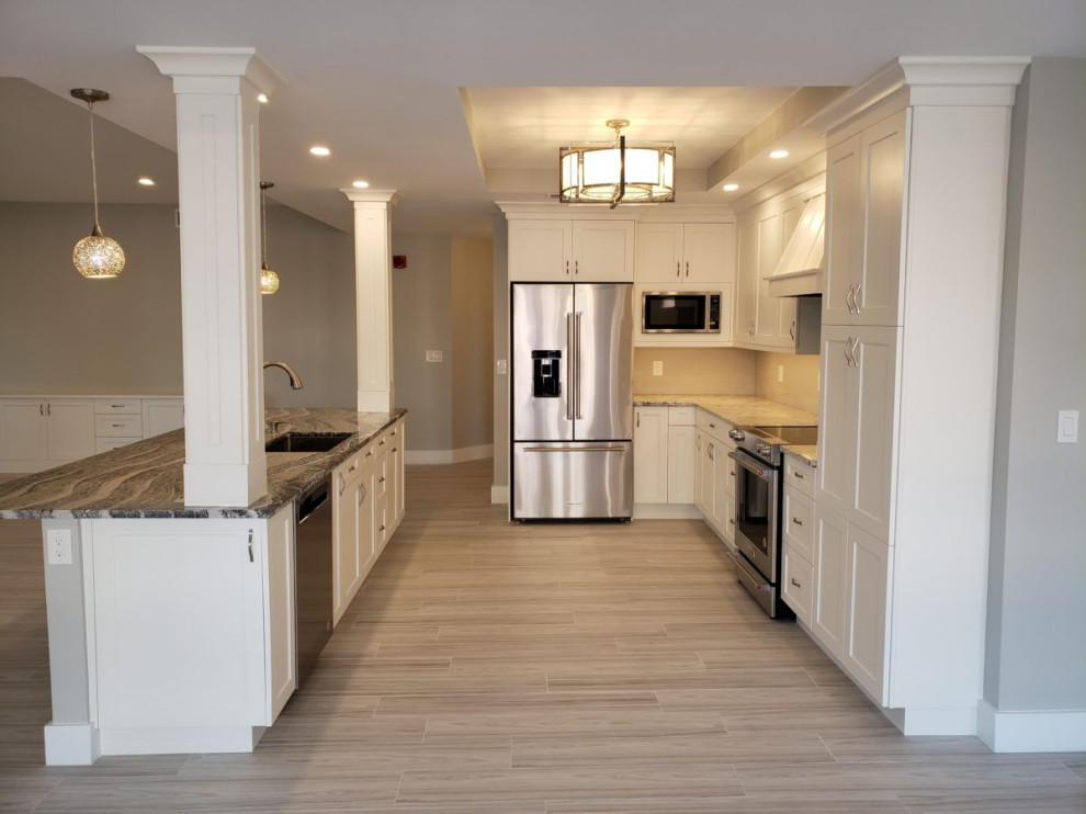 Photo of a mid-sized transitional u-shaped eat-in kitchen in Miami with an undermount sink, recessed-panel cabinets, white cabinets, granite benchtops, beige splashback, subway tile splashback, stainless steel appliances, vinyl floors, a peninsula, grey floor and multi-coloured benchtop.
