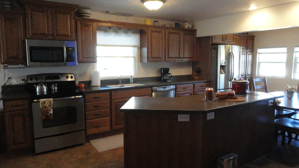 Inspiration for a mid-sized single-wall open concept kitchen remodel with an undermount sink, raised-panel cabinets, medium tone wood cabinets, solid surface countertops, stainless steel appliances, beige walls and an island