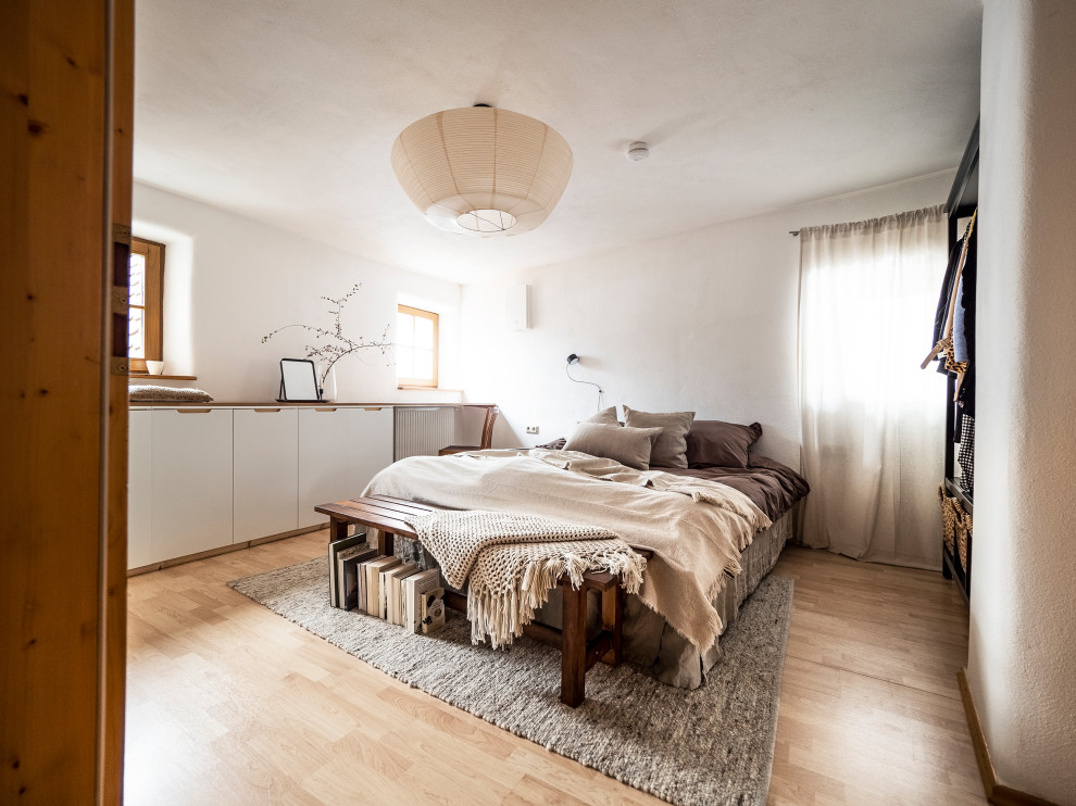 Idee per una camera matrimoniale scandinava di medie dimensioni con pareti bianche, pavimento in laminato, pavimento marrone e carta da parati