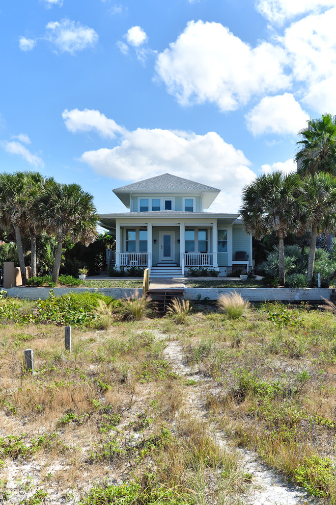 Inspiration for a mid-sized beach style two-storey green exterior in Tampa with vinyl siding and a hip roof.