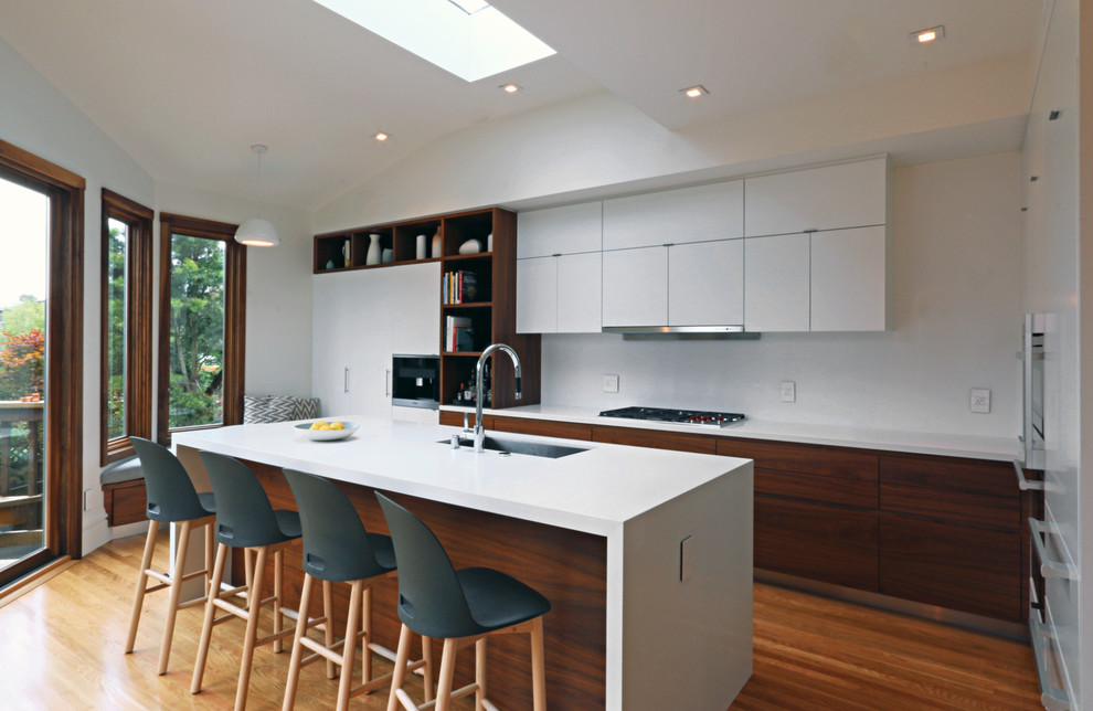 Inspiration for a contemporary kitchen in San Francisco with an undermount sink, flat-panel cabinets, white cabinets, quartz benchtops, white splashback, stainless steel appliances, medium hardwood floors and with island.