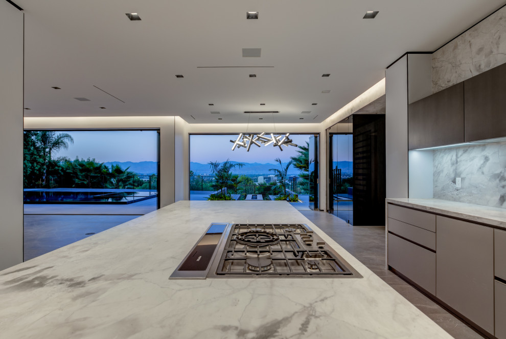 Large contemporary u-shaped kitchen/diner in Los Angeles with a submerged sink, flat-panel cabinets, grey cabinets, marble worktops, white splashback, stone slab splashback, integrated appliances, slate flooring, an island, grey floors and white worktops.