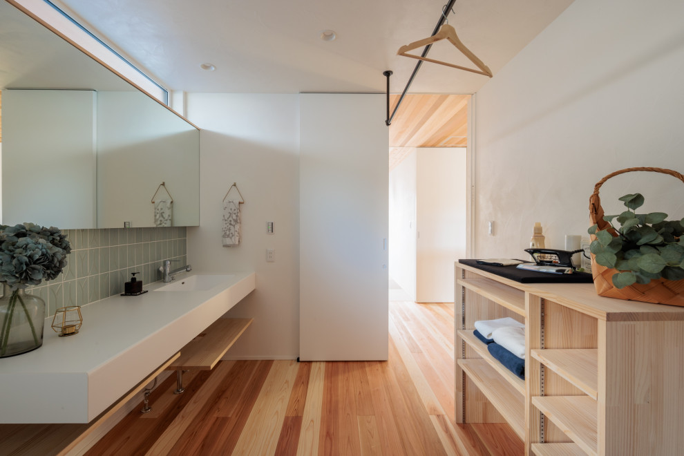 This is an example of a mid-sized midcentury utility room in Other with solid surface benchtops, white walls, medium hardwood floors and white benchtop.