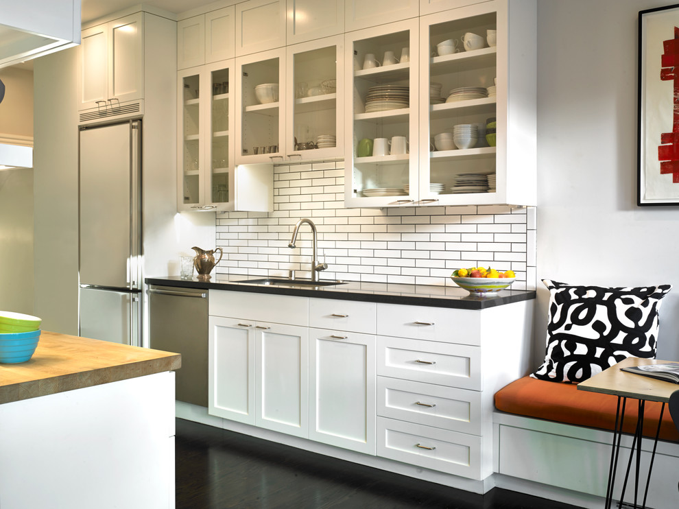 Design ideas for a mid-sized contemporary galley eat-in kitchen in San Francisco with white cabinets, white splashback, subway tile splashback, a drop-in sink, wood benchtops, stainless steel appliances, dark hardwood floors, no island and flat-panel cabinets.