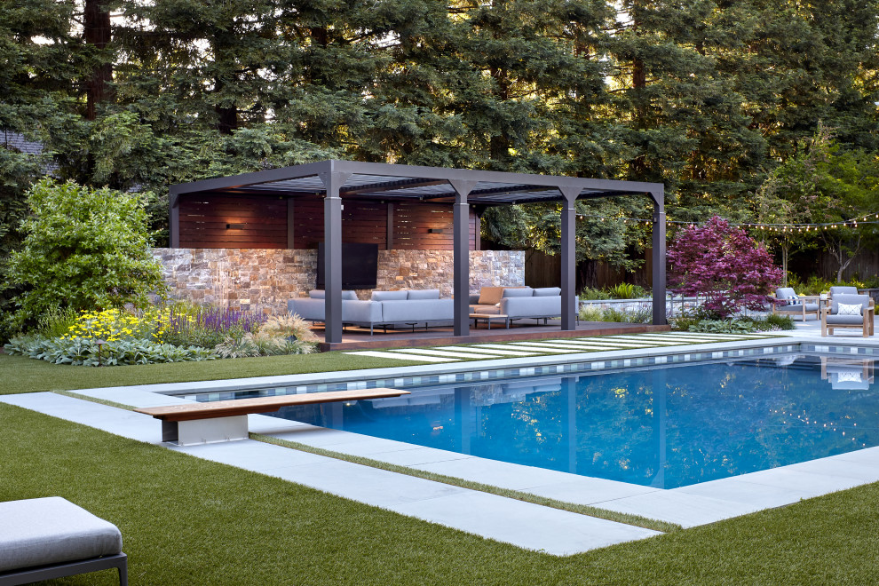 This is an example of an expansive contemporary backyard rectangular lap pool in San Francisco with a hot tub and natural stone pavers.