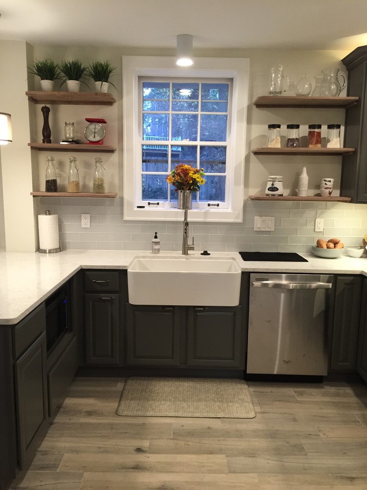 Eat-in kitchen - small transitional u-shaped light wood floor eat-in kitchen idea in Cincinnati with a farmhouse sink, raised-panel cabinets, gray cabinets, quartz countertops, gray backsplash, glass tile backsplash, stainless steel appliances and a peninsula