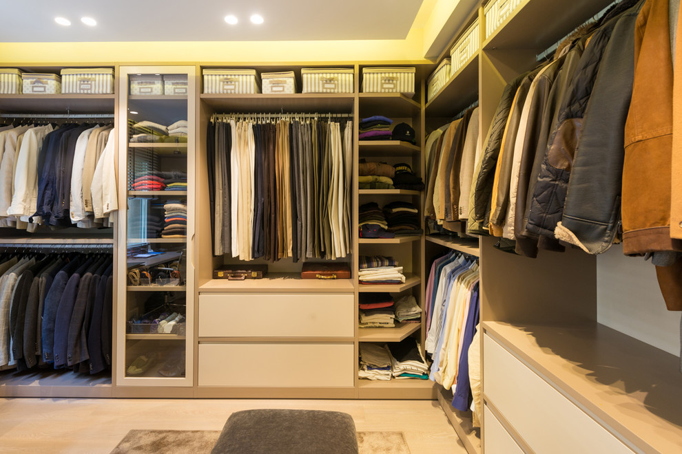 Photo of a mid-sized transitional gender-neutral walk-in wardrobe in Barcelona with open cabinets, light hardwood floors, beige floor and white cabinets.