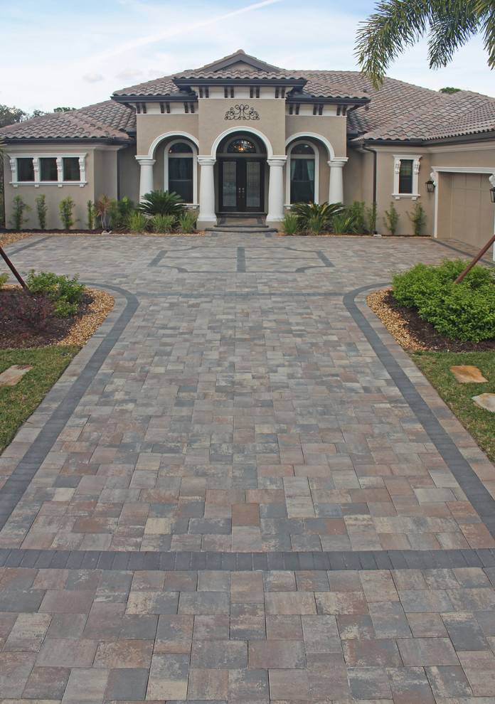 Photo of a large tropical front yard driveway in Tampa with brick pavers.
