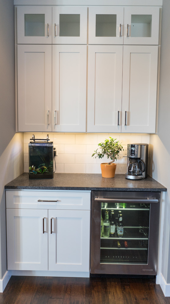 Inspiration for a large transitional u-shaped eat-in kitchen remodel with a farmhouse sink, flat-panel cabinets, white cabinets, granite countertops, white backsplash, ceramic backsplash, stainless steel appliances and an island