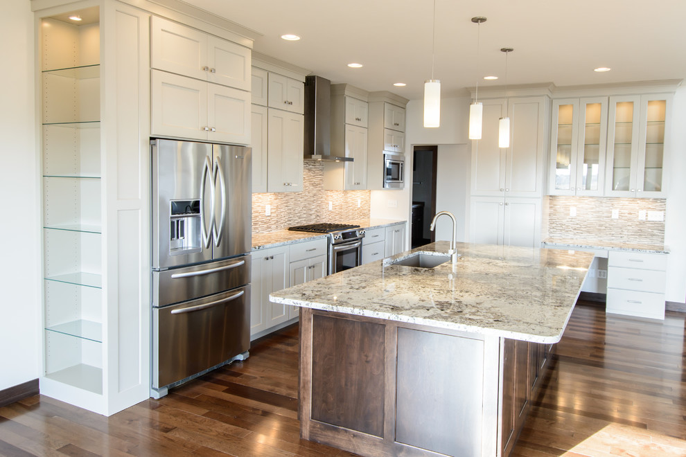 Inspiration for a mid-sized transitional l-shaped medium tone wood floor and brown floor open concept kitchen remodel with a farmhouse sink, shaker cabinets, white cabinets, stainless steel appliances, an island, granite countertops, multicolored backsplash and matchstick tile backsplash