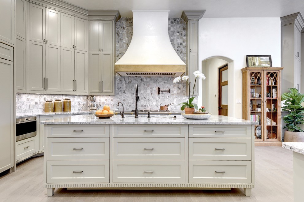 Kitchen - mediterranean l-shaped light wood floor and beige floor kitchen idea in Austin with an undermount sink, recessed-panel cabinets, gray cabinets, gray backsplash, an island and gray countertops