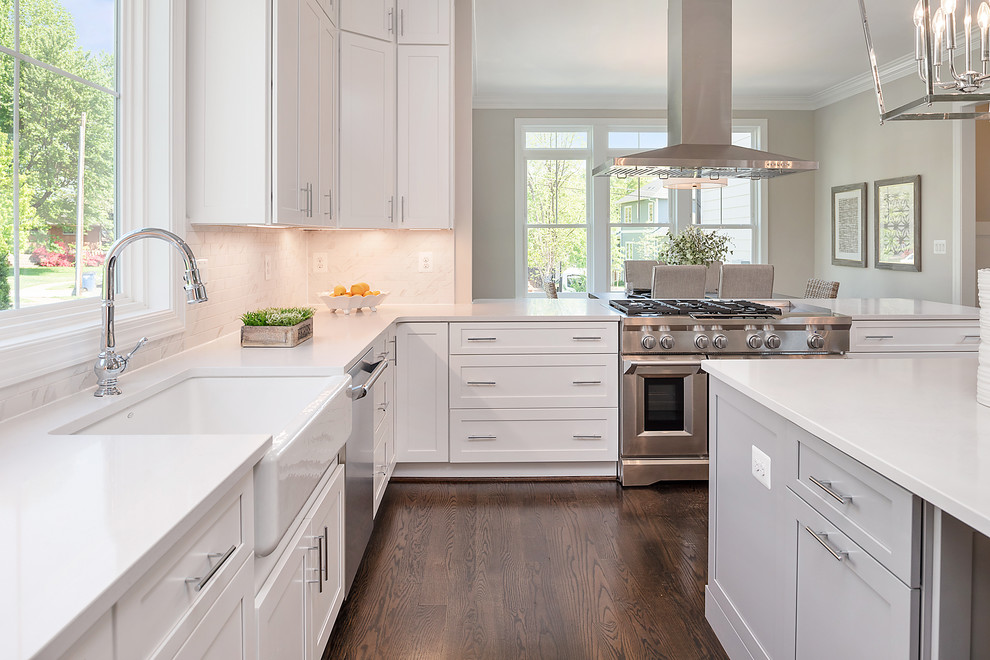 Inspiration for a transitional l-shaped eat-in kitchen in DC Metro with a farmhouse sink, shaker cabinets, white cabinets, stainless steel appliances, dark hardwood floors, brown floor and white benchtop.