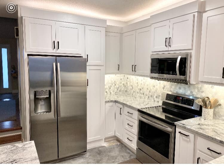 Photo of a medium sized modern kitchen/diner in Kansas City with a double-bowl sink, shaker cabinets, white cabinets, granite worktops, multi-coloured splashback, mosaic tiled splashback, stainless steel appliances, concrete flooring, a breakfast bar and multicoloured worktops.
