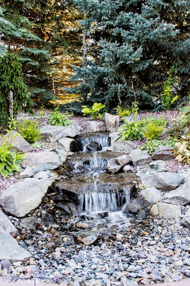 Inspiration for a mid-sized traditional sloped full sun garden for spring in Other with with pond and gravel.