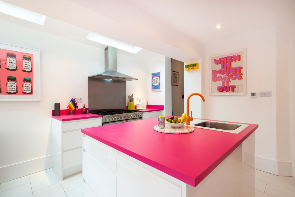 Design ideas for a mid-sized eclectic l-shaped open plan kitchen in London with an integrated sink, flat-panel cabinets, white cabinets, solid surface benchtops, pink splashback, stainless steel appliances, ceramic floors, with island, white floor and pink benchtop.