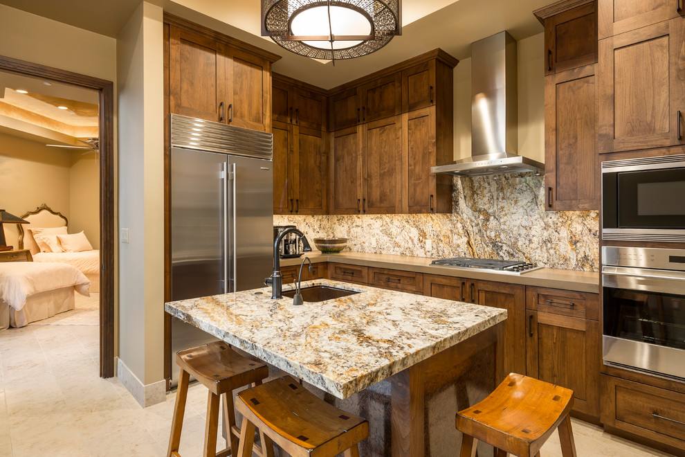 Inspiration for a transitional l-shaped kitchen remodel in Phoenix with an undermount sink, shaker cabinets, dark wood cabinets, stainless steel appliances and an island