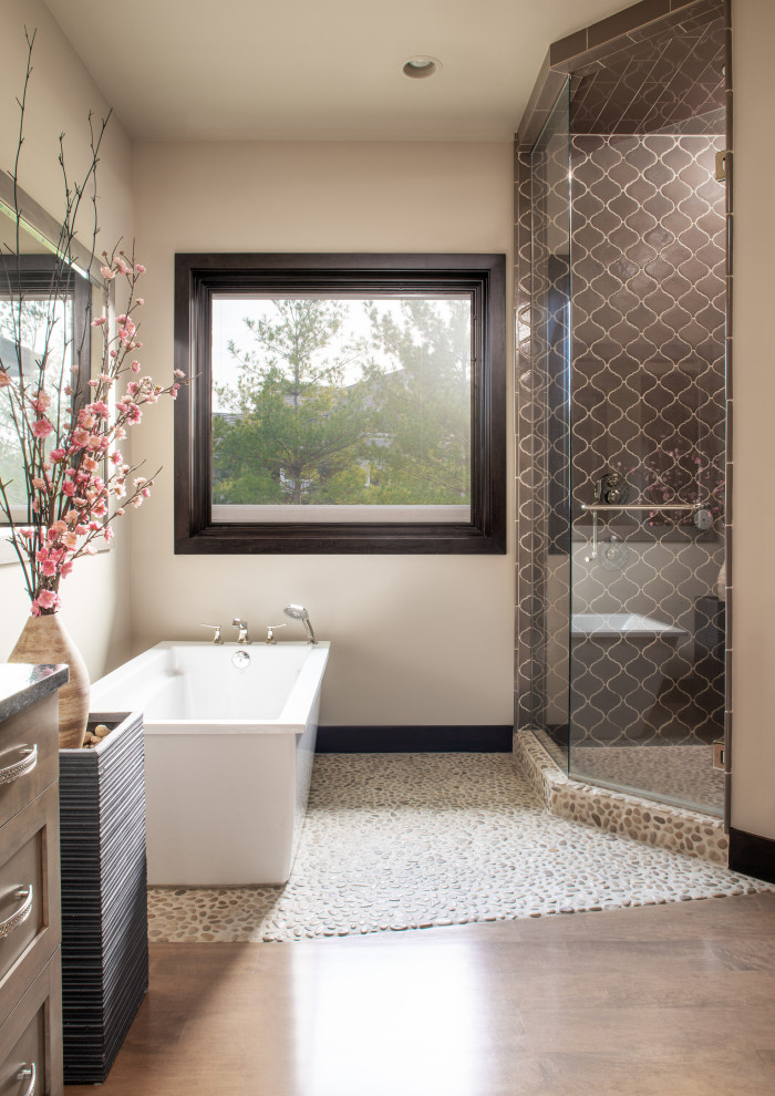 Photo of a large transitional master bathroom in Omaha with shaker cabinets, medium wood cabinets, a freestanding tub, an alcove shower, beige tile, brown tile, porcelain tile, beige walls, medium hardwood floors, brown floor, a hinged shower door and black benchtops.