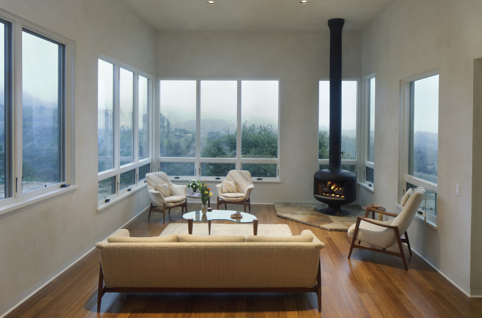 Mid-sized modern enclosed living room in Santa Barbara with white walls, bamboo floors and a wood stove.