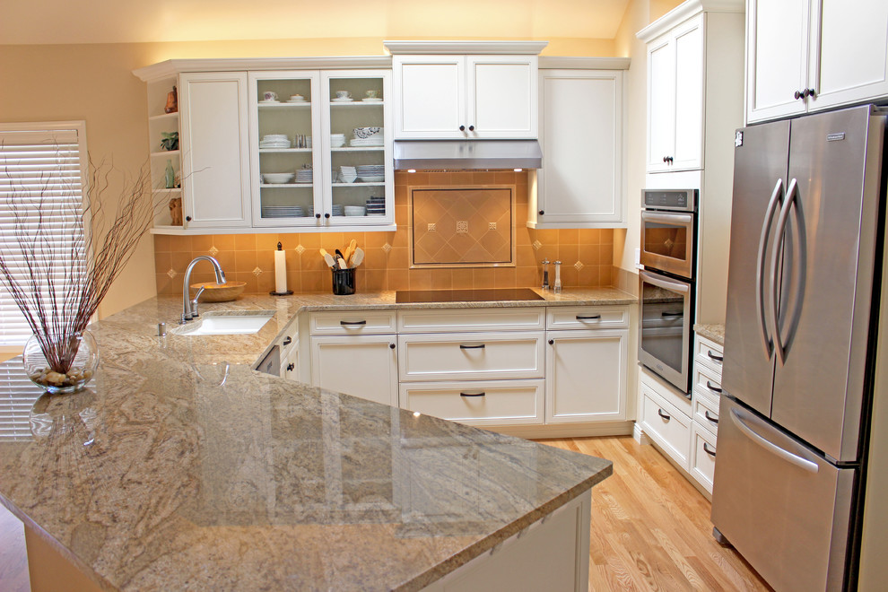 Photo of a mid-sized traditional l-shaped eat-in kitchen in Seattle with a double-bowl sink, recessed-panel cabinets, white cabinets, beige splashback, stainless steel appliances, light hardwood floors, a peninsula and soapstone benchtops.