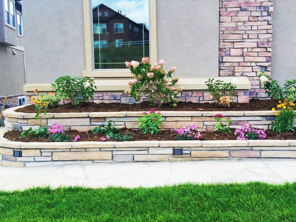 This is an example of a mid-sized contemporary front yard garden in Denver with a retaining wall and natural stone pavers.
