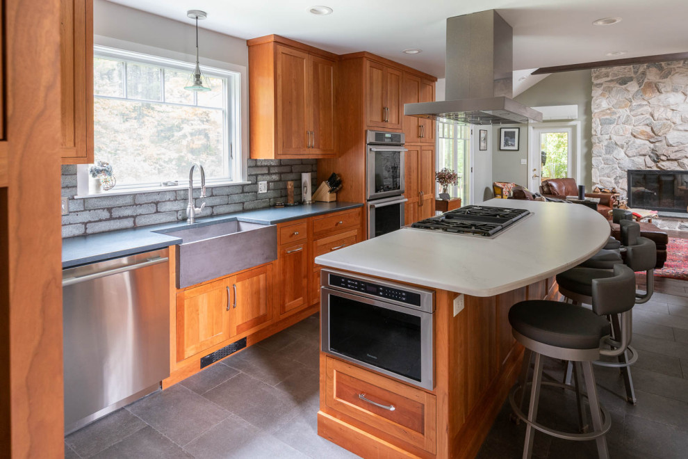Inspiration for a large transitional l-shaped porcelain tile and gray floor eat-in kitchen remodel in Boston with a farmhouse sink, shaker cabinets, medium tone wood cabinets, quartz countertops, gray backsplash, porcelain backsplash, stainless steel appliances, an island and white countertops